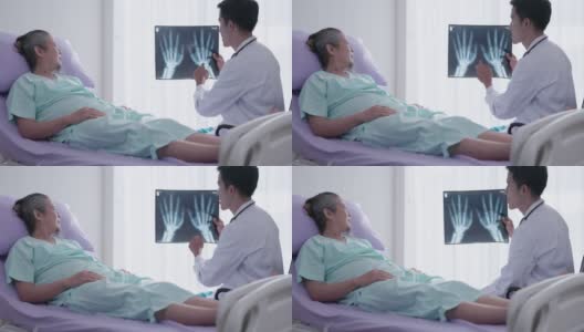 在医院里，一位很好的男整形外科医生和一位老人在病床上讨论x光扫描。高清在线视频素材下载