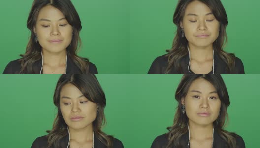 年轻的亚洲女人看起来很悲伤，在一个绿色屏幕的工作室背景高清在线视频素材下载