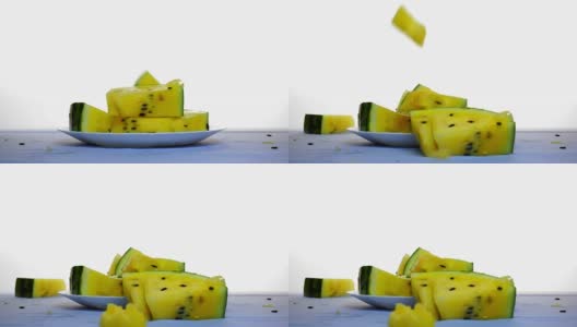 桌上放着一片片黄色的西瓜。另一片从上面掉下来高清在线视频素材下载