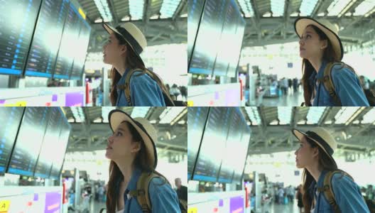 一个漫不经心的年轻女人在候机楼看航班时刻表。年轻妇女独自乘飞机旅行。高清在线视频素材下载