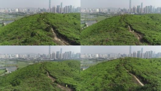 女超级马拉松运动员在现代城市旁边的山上奔跑的鸟瞰图高清在线视频素材下载