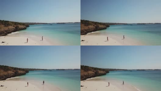 一对情侣在龙目岛的粉色沙滩上散步。这个地方是一块隐藏的宝石，不会被游客破坏。孤独和平静的感觉，海浪轻轻在沙滩上蔓延。色彩斑斓的悬崖高清在线视频素材下载