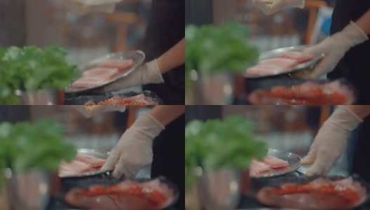 亚洲餐厅的员工戴着防护手套为顾客服务五花肉。高清在线视频素材下载