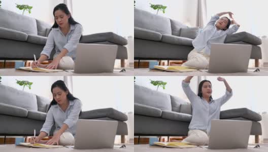 年轻的亚洲女商人正在笔记本上写一个新的项目。她累了，伸懒腰，躺在客厅的沙发上。在家工作，商业女性和工作理念。高清在线视频素材下载