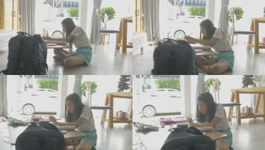 亚洲女孩一边做作业一边在家学习在线课程，社交距离的生活方式概念。高清在线视频素材下载