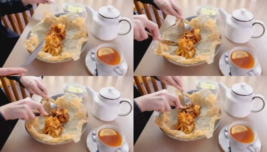 Woman is eating julienne baked in dough served on a plate on baker paper with tea and butter. Hands close-up.高清在线视频素材下载