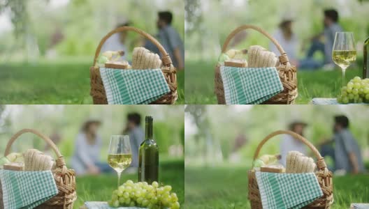 公园里的白葡萄和一瓶白葡萄酒，背景是一对浪漫的情侣高清在线视频素材下载