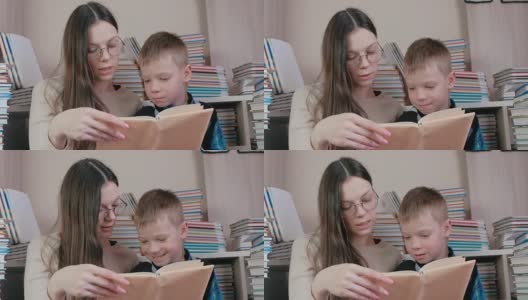 妈妈坐在书中间给儿子读了一本书。妈妈的眼镜。高清在线视频素材下载