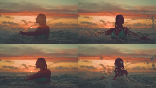 剪影:年轻女子微笑着在日落时分用手泼海水。高清在线视频素材下载