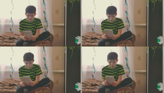 男孩坐在沙发上玩平板电脑，玩游戏，上网高清在线视频素材下载