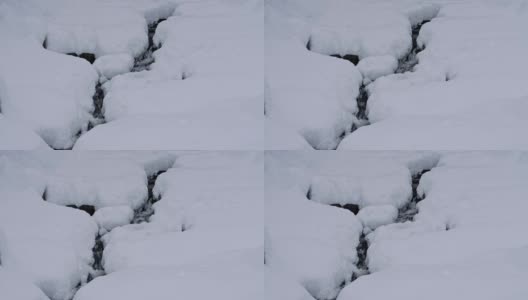 冬天，深雪，一条小溪，白雪覆盖的石头，白色的帽子，特写镜头，实时高清在线视频素材下载