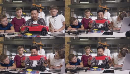 在现代学校的桌子上，年轻的韩国电子工程师和孩子们用螺丝刀拆卸机器人高清在线视频素材下载