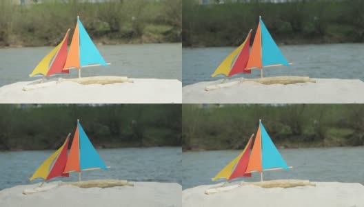 沙滩上是自制的玩具帆船，背景是山河高清在线视频素材下载