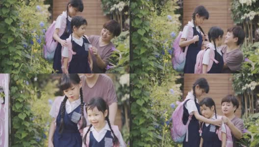 回到学校的亚洲华人妈妈在早上从家到学校的前院里帮女儿们戴上校名标签高清在线视频素材下载