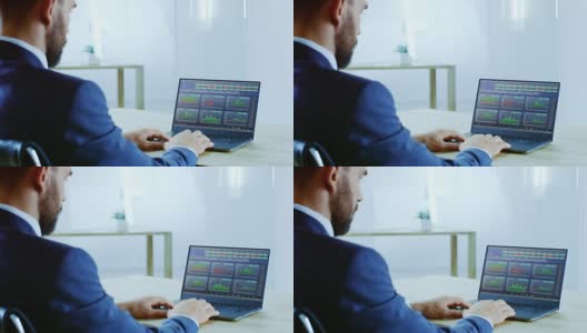 在肩膀上的成功商人在笔记本电脑上工作，屏幕显示股票市场股票行情信息。市场的兴衰。办公室是明亮和现代的。高清在线视频素材下载