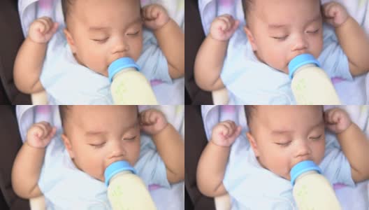 婴儿在婴儿车里吃奶瓶里的牛奶高清在线视频素材下载