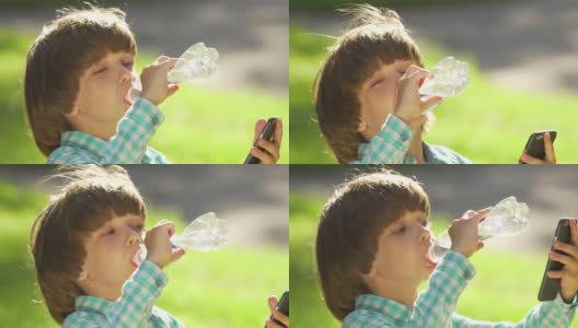 在夏天的公园里，快乐的小男孩喝着塑料瓶里的清水。孩子的肖像在户外饮水日落。关爱儿童保健，阳光热，特写高清在线视频素材下载