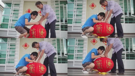 亚洲华人父亲和儿子准备大红灯笼在他们家的前院在中国新年前夕高清在线视频素材下载