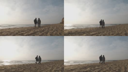 在多云的日出或日落时，幸福的情侣漫步在野生的海滩上高清在线视频素材下载