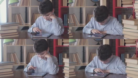 快乐的小男孩翻动着平板电脑的屏幕。学校考试。高清在线视频素材下载