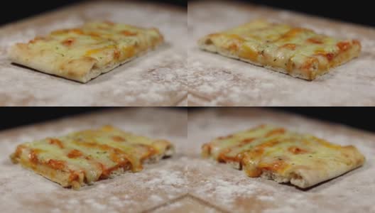 平面包披萨由奶酪在砧板上与面粉在黑色的背景下慢慢旋转高清在线视频素材下载