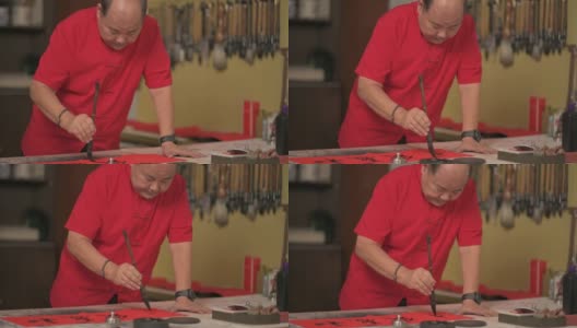 亚洲华人男性练习书法，为即将到来的中国新年庆祝家庭装饰目的与繁荣和良好的措辞写在一张红色的纸上高清在线视频素材下载