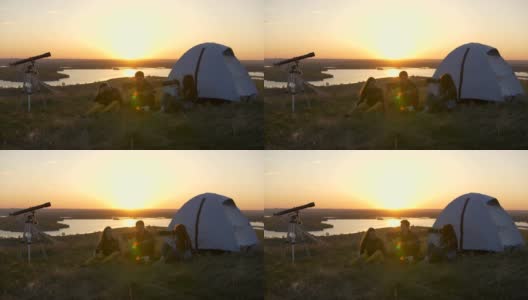 日落时分，年轻的朋友们坐在帐篷附近，弹着吉他唱歌高清在线视频素材下载