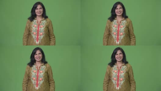 成熟快乐美丽的印度女人微笑着，穿着传统的衣服在绿色的背景下高清在线视频素材下载