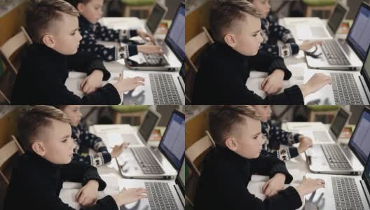 两个小男孩坐在他们的笔记本电脑前学习编程。高清在线视频素材下载
