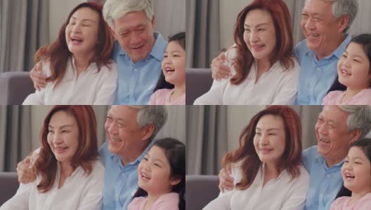 亚洲祖父母在家里和孙女聊天。中国老年人、老一代、爷爷奶奶家人时间和小女孩孩子在客厅沙发上放松的概念。缓慢的运动。高清在线视频素材下载