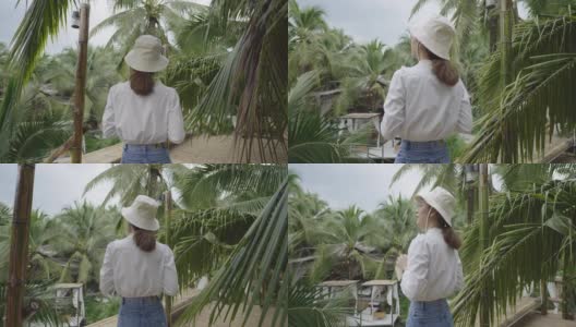 在椰子树上喝椰子汁的女人高清在线视频素材下载