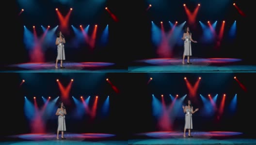 一位女歌手在彩色探照灯照亮的舞台上演唱歌曲高清在线视频素材下载