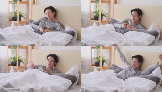 男人打呵欠和伸懒腰在床上使用手机高清在线视频素材下载