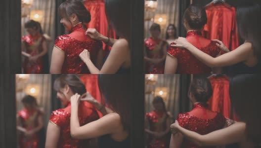 在传统精品店，一名亚洲华人女子在姐姐的帮助下，对着镜子试穿中国传统旗袍高清在线视频素材下载
