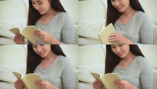放松的亚洲女人读书坐在客厅的沙发上抱着书读。18、少妇舒心读书，读书开卷休闲心灵。幸福美女人笑脸幸福时光高清在线视频素材下载