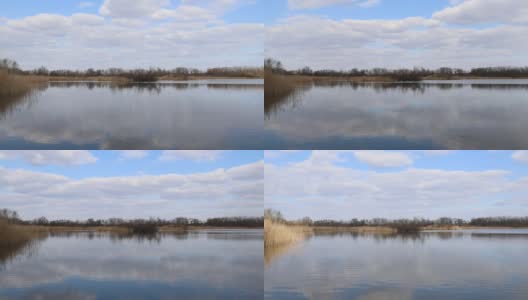 在捷克共和国池塘杂草的美丽风景的时间推移。天鹅漂浮在水面上，白云在蓝天上流动，光影交替。高清在线视频素材下载