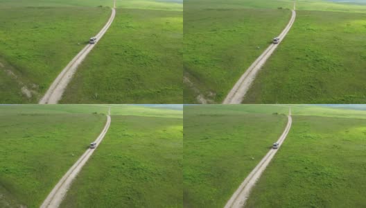 一条山间公路的俯视图。无人机拍摄的一条蜿蜒的道路穿过绿色的山丘和山脉。汽车在路上行驶高清在线视频素材下载