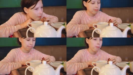 快乐的女孩在咖啡厅喝茶，吃蛋糕马卡龙。十几岁的女孩坐在桌子和吃在咖啡厅里面。爱吃甜食的孩子吃美味的蛋糕。高清在线视频素材下载