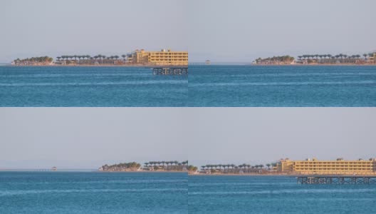 热带度假胜地的海岸线，棕榈树，酒店建筑和蓝色的海水在前面高清在线视频素材下载