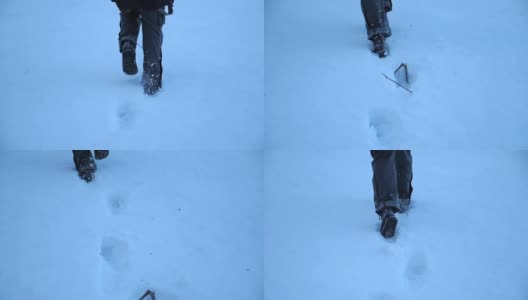 后视图的男性的脚走过在晚上的雪地在田野。一个面目全非的家伙在冬季旅行中享受自由。假期的概念。特写慢动作高清在线视频素材下载