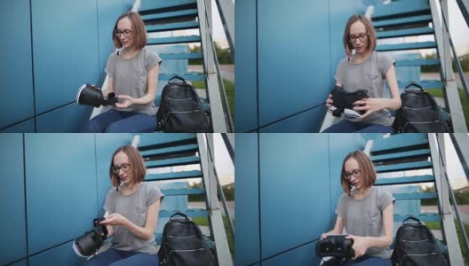 一个戴眼镜的小女孩手里拿着一副蓝色背景的虚拟现实眼镜。带着vr眼镜坐在楼梯上的微笑女人。高清在线视频素材下载