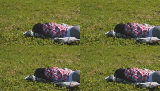梳着蓝色非洲辫的陌生女人睡在公园的草坪上。高清在线视频素材下载