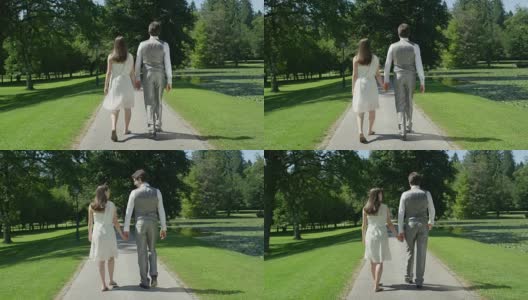 慢镜头:一对年轻的幸福夫妇手牵着手在公园里散步，互相凝视高清在线视频素材下载