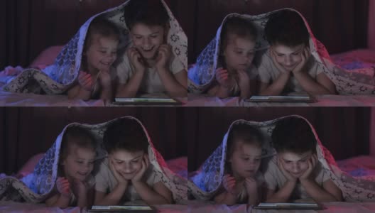 弟弟和妹妹用平板电脑看视频。霓虹灯照明。高清在线视频素材下载