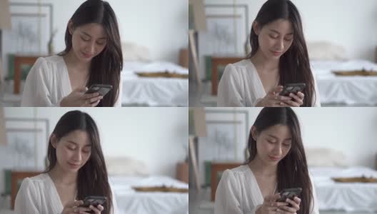 年轻的亚洲女性在卧室里使用手机高清在线视频素材下载
