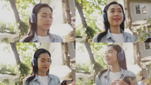 年轻美丽的亚洲女人戴着耳机从智能手机音乐微笑快乐的夏天花园。少年是快乐的周末。假日旅行。生活方式的概念高清在线视频素材下载