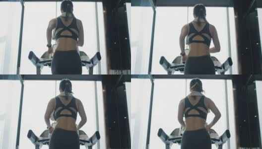 年轻女子在健身房的跑步机上锻炼和慢跑高清在线视频素材下载