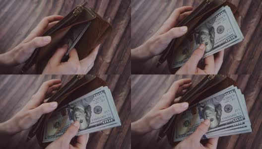 俯视图，一个女人在数，从她的棕色皮夹里拿出美元。女性拿着钱包，背景是木制的。慢动作高清在线视频素材下载