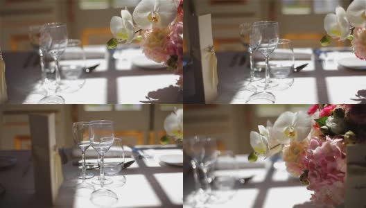 菜单上的单杯空酒，水和粉红色的鲜花花束在白色桌布上安排精致的餐饮跟踪微距特写。节日优雅的餐桌，在餐厅，咖啡厅宴会上用餐高清在线视频素材下载