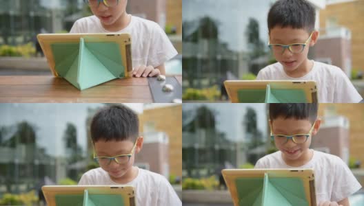 一个男孩在平板电脑上玩游戏高清在线视频素材下载